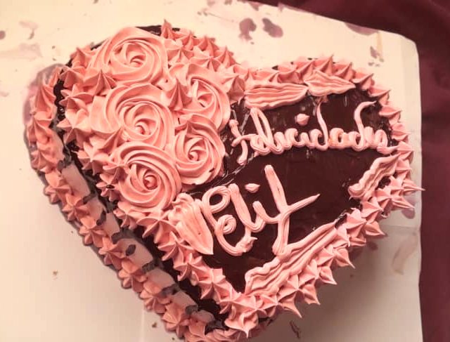 Cake de chocolate en forma de corazón con rosas de merengue y la palabra Felicidades
